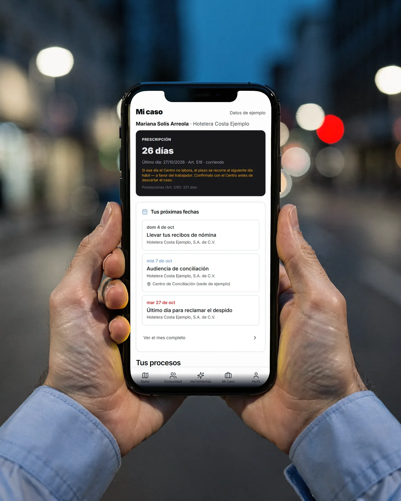 Manos sosteniendo un teléfono con el panel Mi caso de la app: el contador del plazo, las próximas fechas y los pasos del caso (datos de ejemplo).
